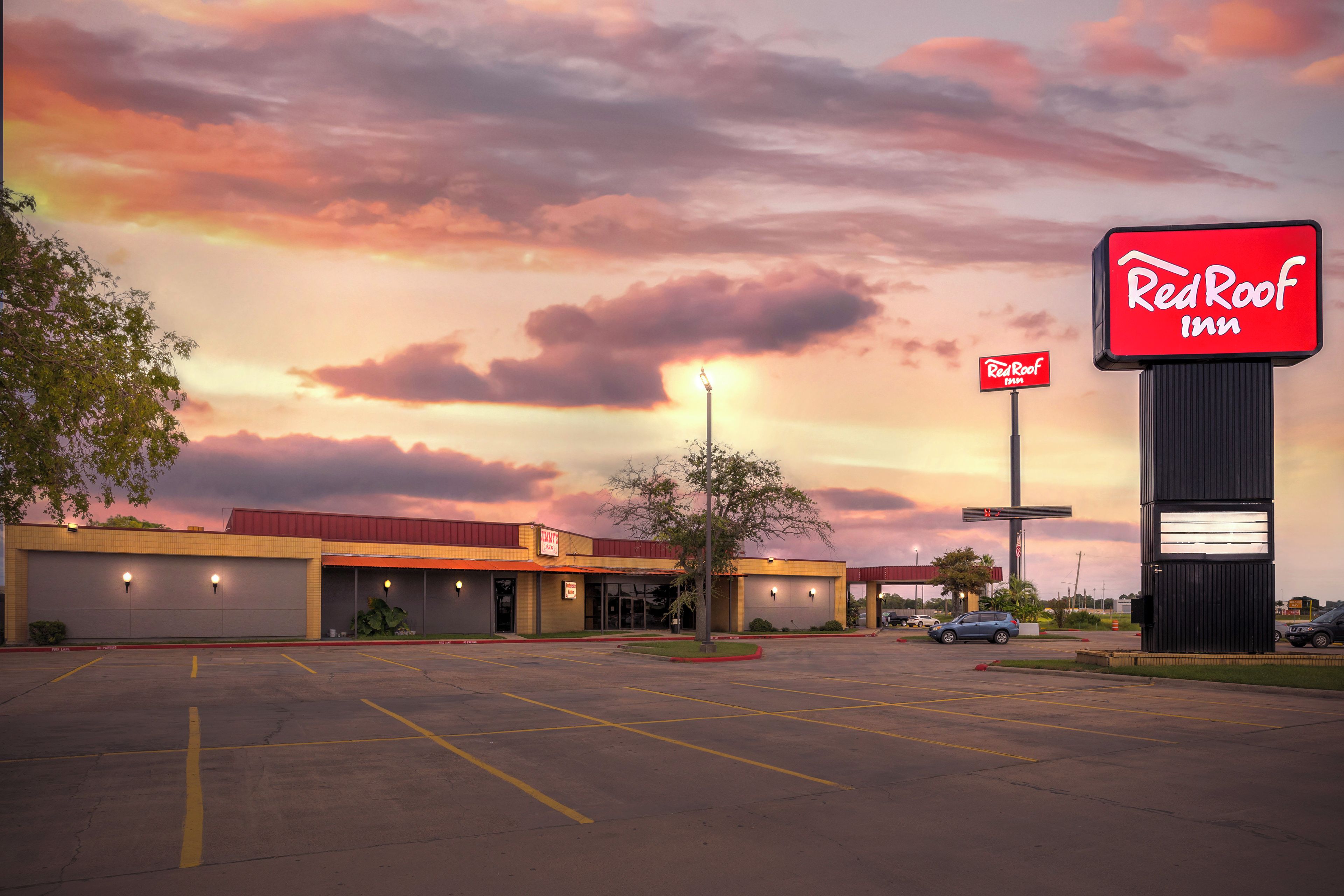 A Red Roof Inn with a parking lot and a building with a flat roof and a sign.