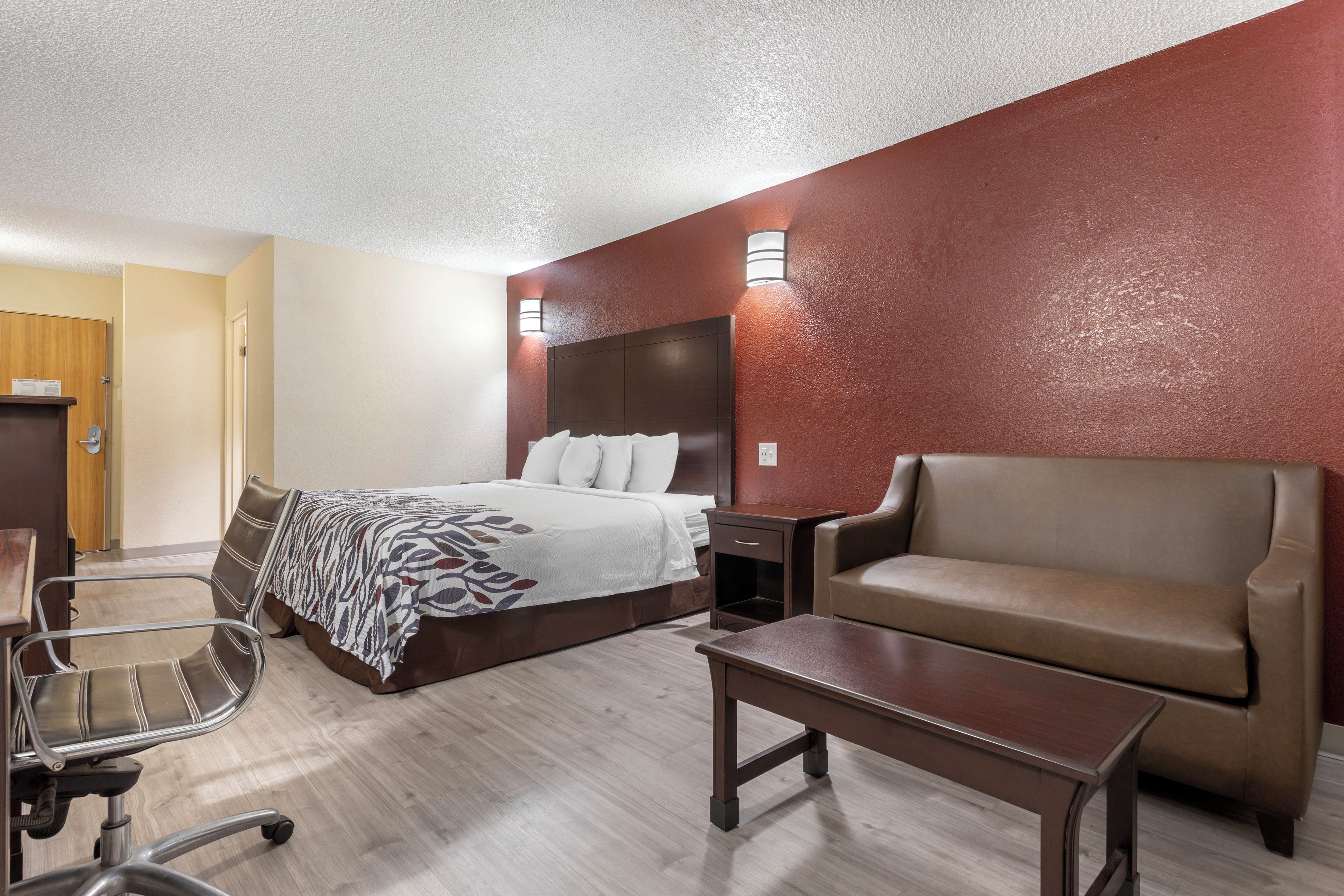 Una habitación de hotel con una cama, un sofá, un escritorio y una silla.