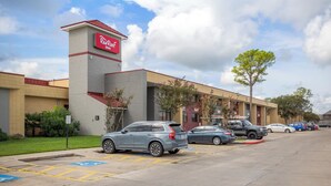 Un hôtel Red Roof Inn doté d’un parking, avec des places de stationnement réservées aux personnes handicapées, et un ciel dégagé.