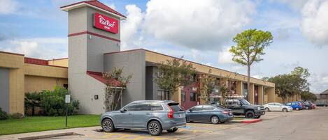 A Red Roof Inn with a parking lot, marked handicapped parking, and a clear sky.