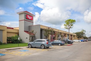 Un hôtel Red Roof Inn doté d’un parking, avec des places de stationnement réservées aux personnes handicapées, et un ciel dégagé.