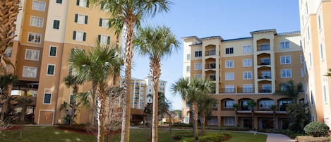 A multi-story hotel with balconies, a landscaped garden, and a pathway.