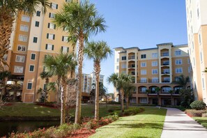A multi-story hotel with balconies, a landscaped garden, and a pathway. - Lake Buena Vista Resort Village & Spa (Orlando)