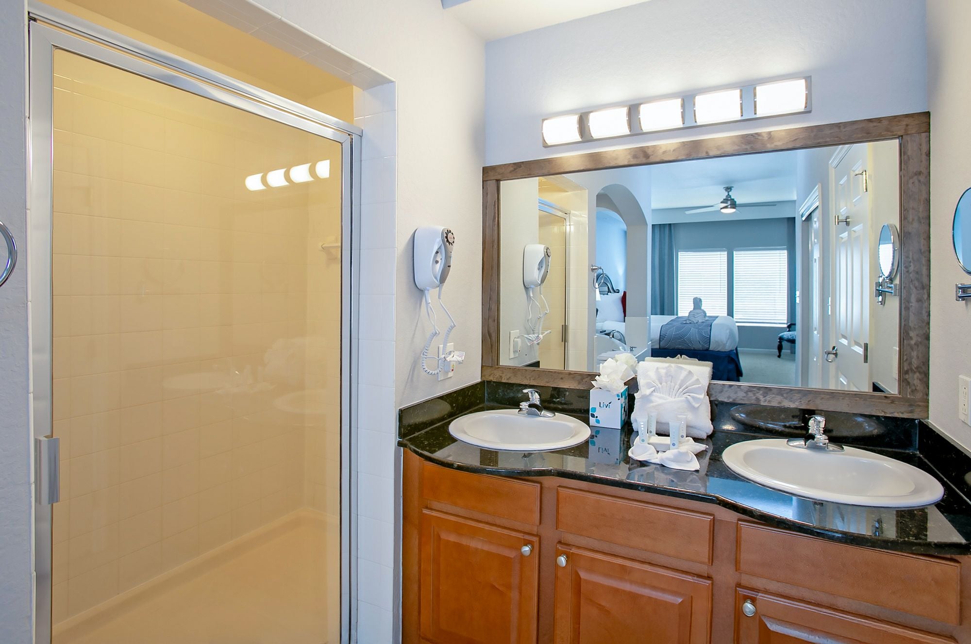 A bathroom with two sinks, a mirror, and a shower.