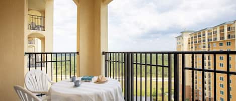 A balcony with a table and chairs, a view of a building, and a railing.