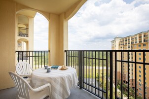 Uma varanda com mesa e cadeiras, vista de um edifício e um corrimão.