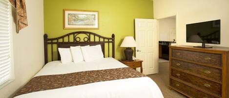 A hotel room with a bed, a dresser, a television, and a painting on the wall.