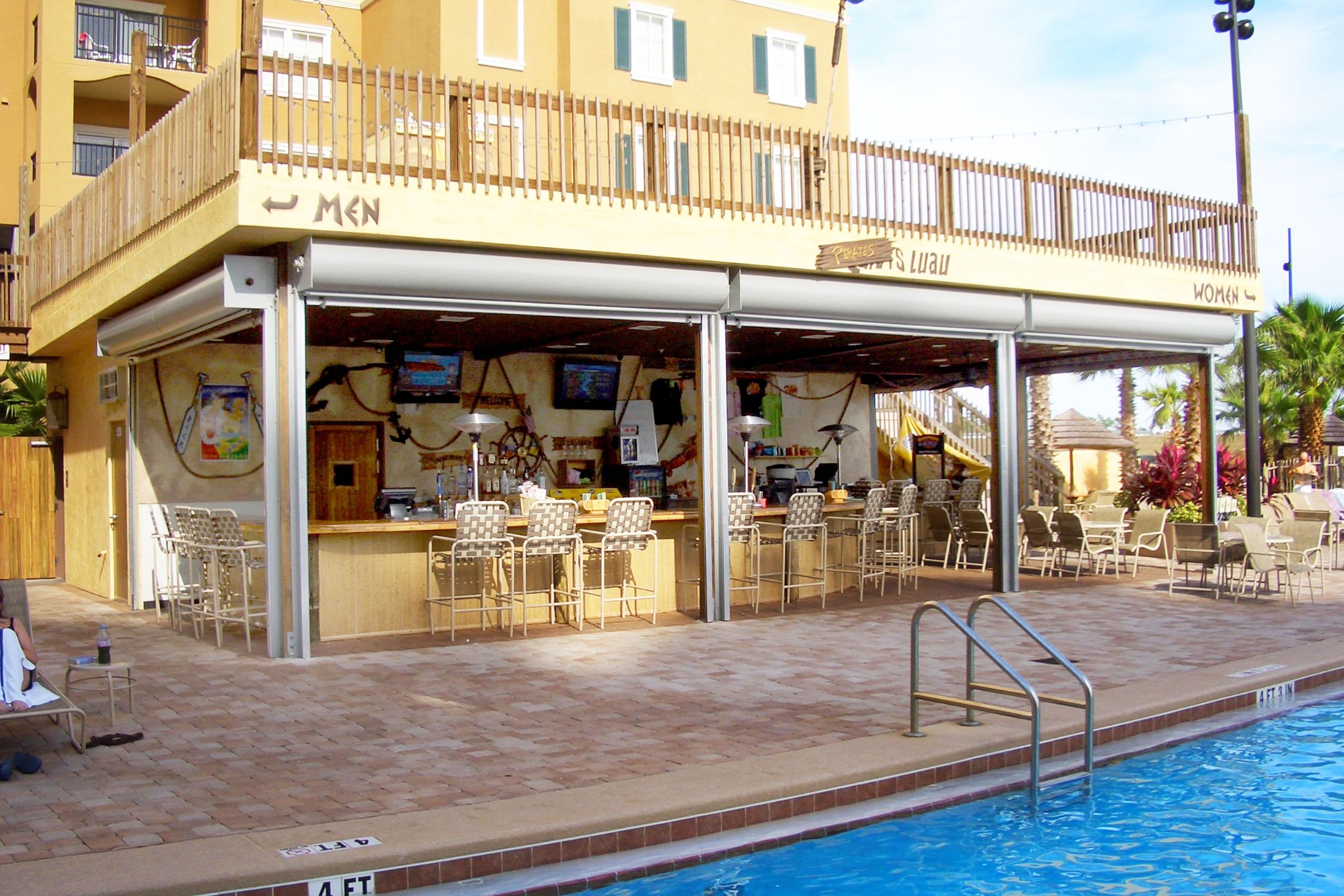 Un bar junto a la piscina con asientos exteriores y una piscina.