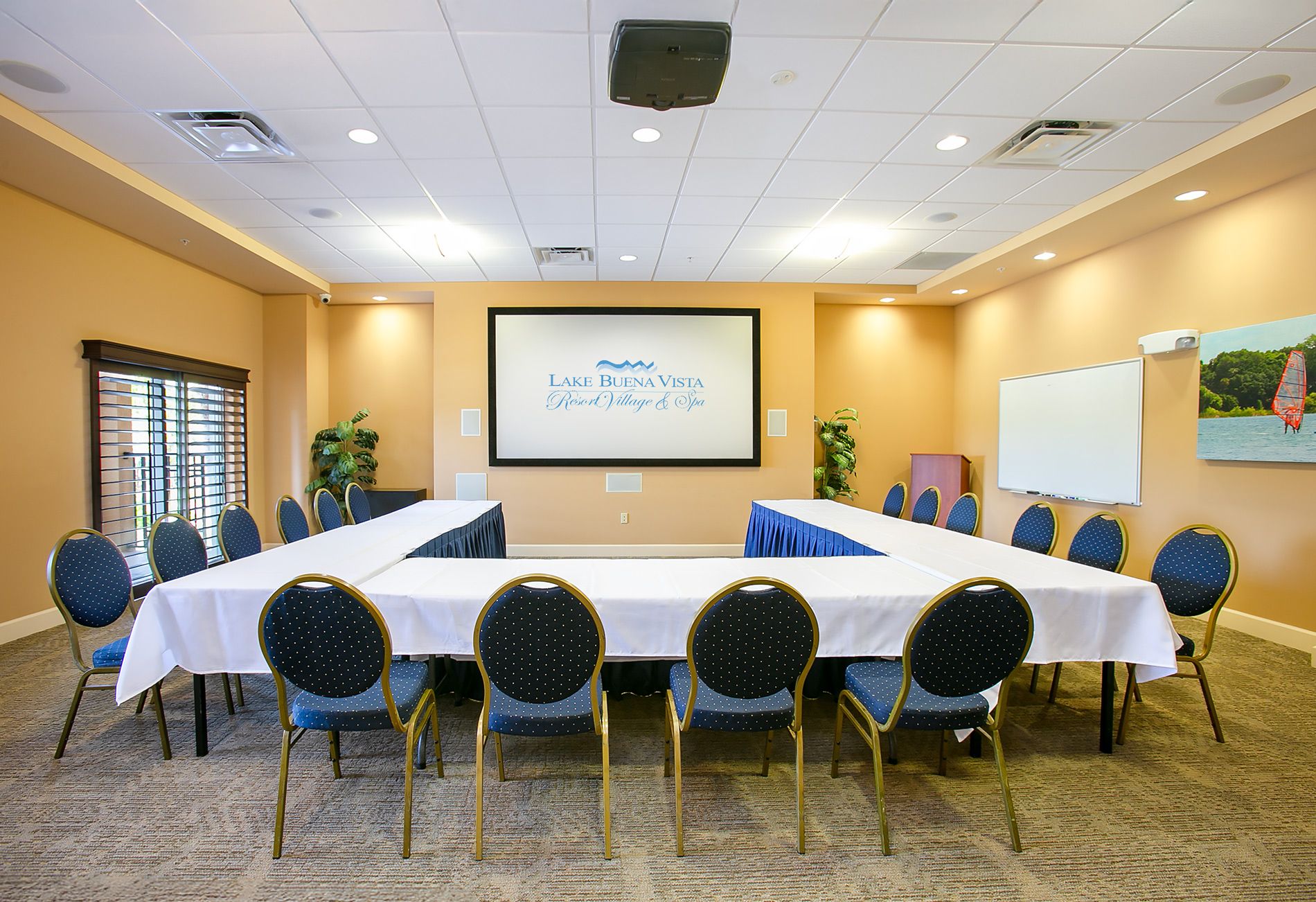 A conference room with a long table, chairs, a projector screen, and a whiteboard.
