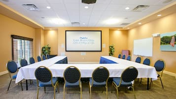 A conference room with a long table, chairs, a projector screen, and a whiteboard.