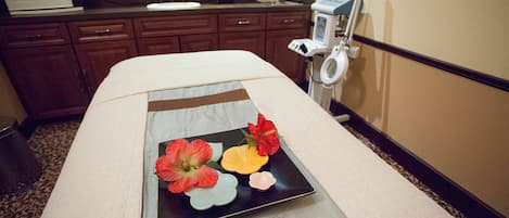 Une chambre d’hôtel comprenant un lit, une table de chevet agrémentée d’un arrangement floral, un lavabo et un appareil à laver le linge.