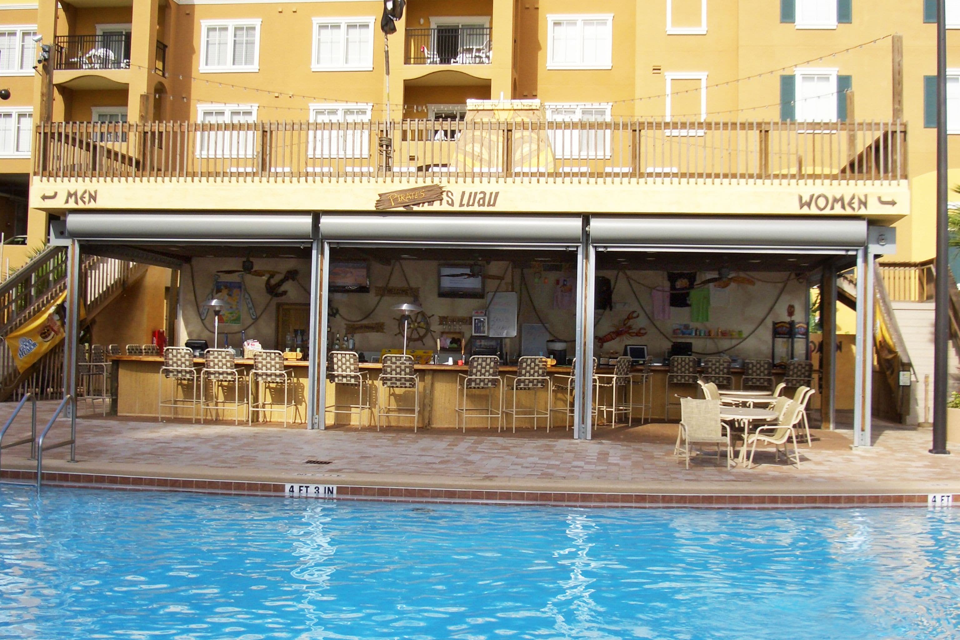 A poolside bar with separate seating for men and women, a lifeguard stand, and a pool with a depth marker.