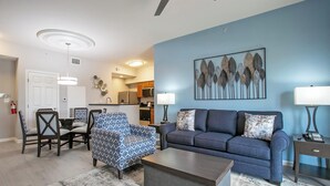 A living room with a blue sofa, patterned armchair, and coffee table.