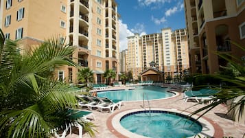 A hotel pool area with multiple lounge chairs and a circular hot tub.
