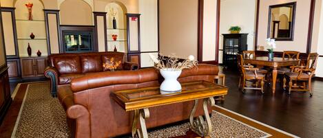 A spacious living room with a leather sofa, a wooden coffee table, and a dining area with wooden chairs and a table.