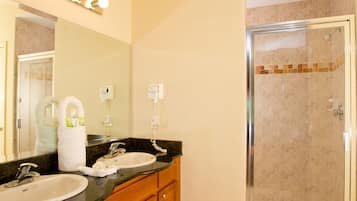 A bathroom with two sinks, a mirror, and a glass-enclosed shower.