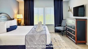 A hotel room with a bed, a dresser, a chair, a television, and a ceiling fan.