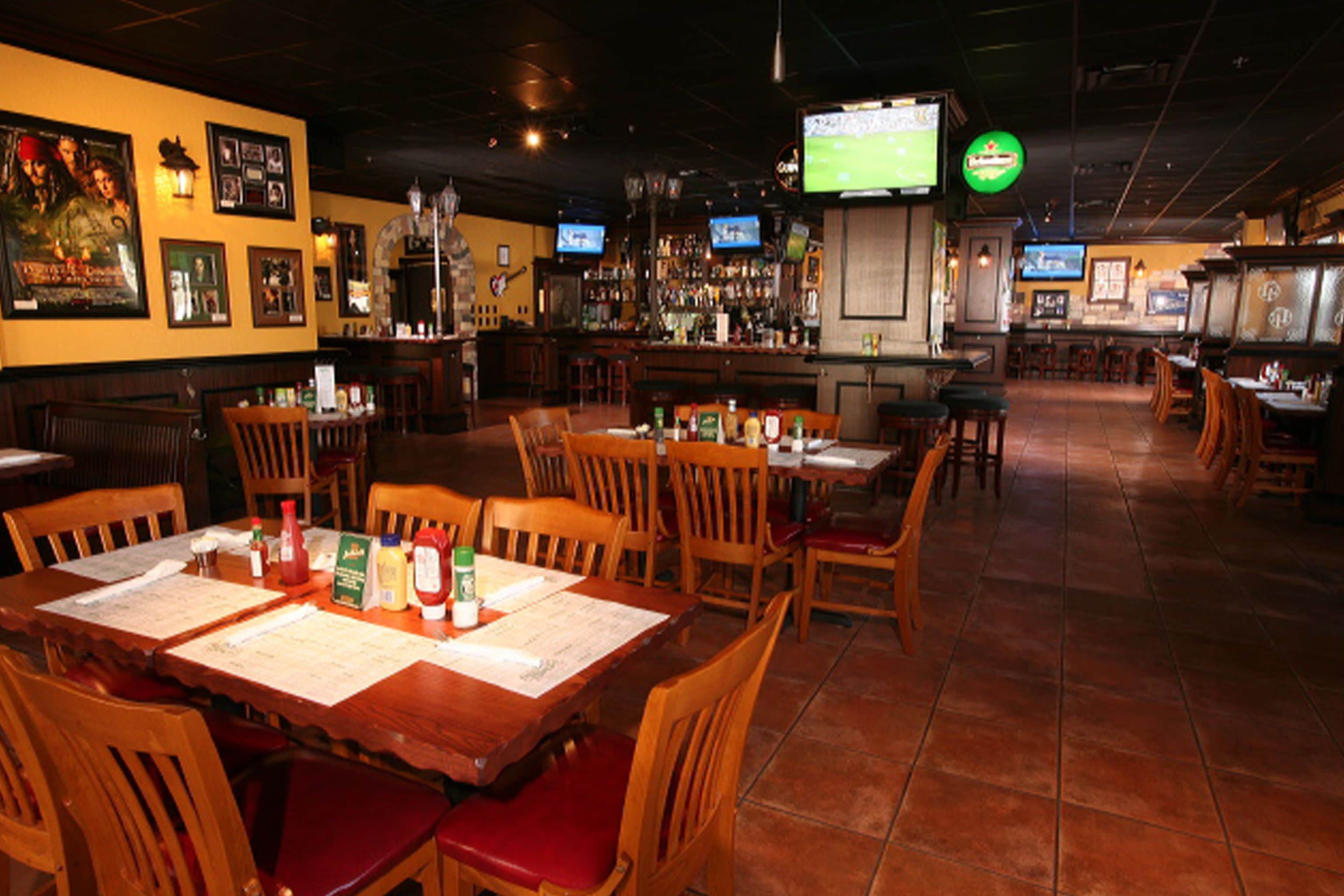 A restaurant with wooden tables and chairs, a bar area, and multiple televisions.