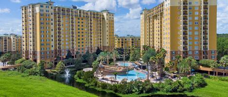 A hotel complex with multiple high-rise buildings, a central swimming pool, and surrounding greenery.