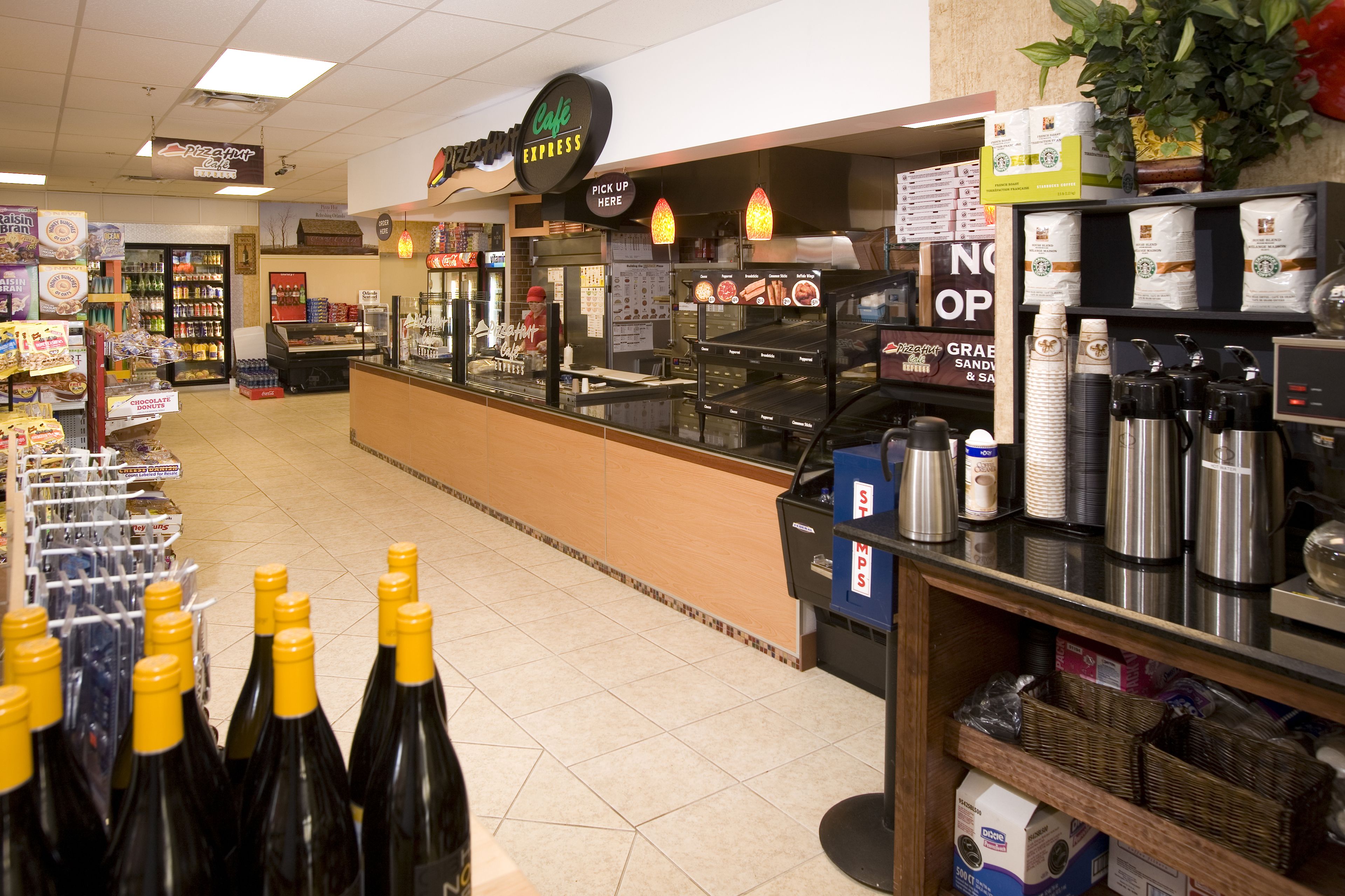 A coffee shop with a counter, a display of bottled beverages, and a variety of food items.