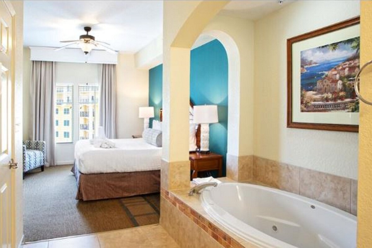 Een hotelkamer met een bed, een badkamer met een bad en uitzicht op de stad.