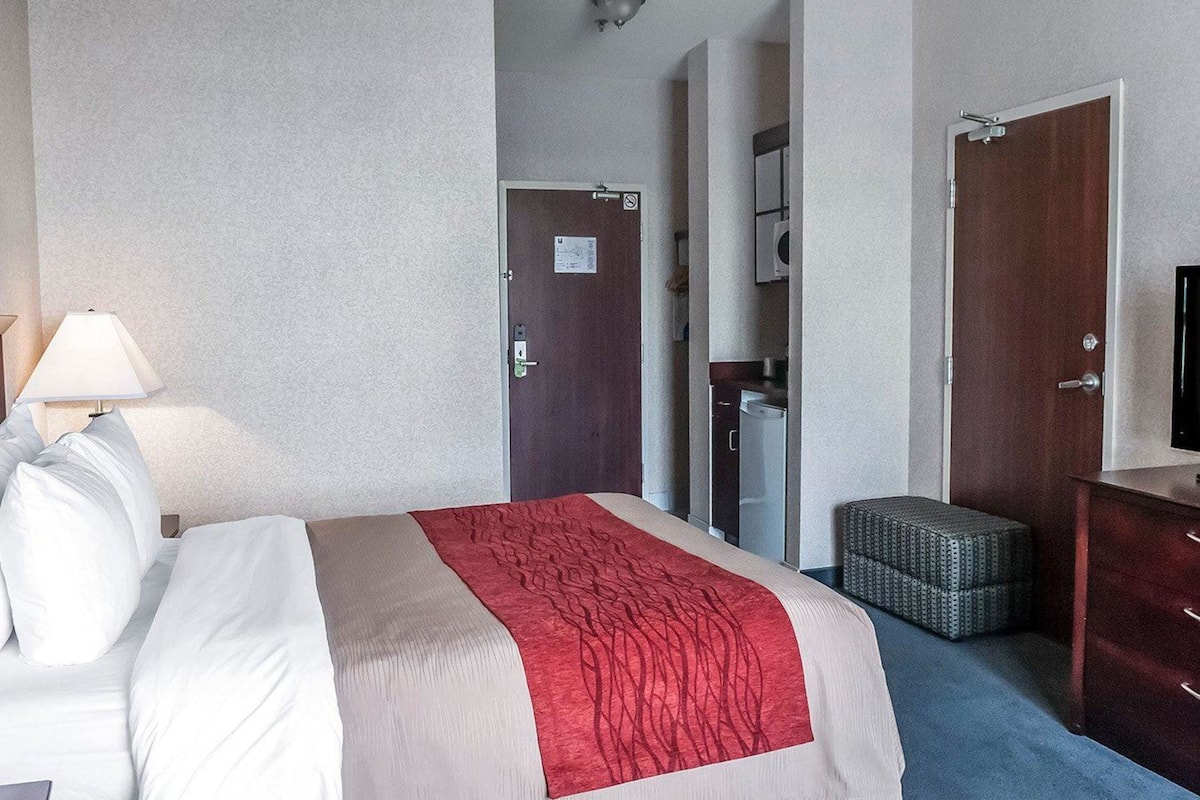 Habitación de hotel con cama, escritorio, silla, cómoda y espejo.