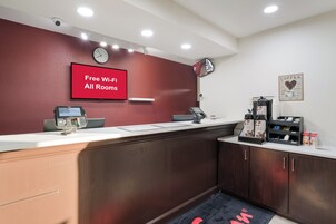 Mostrador de recepción con pantalla digital, un reloj y un cartel que indica acceso a Wi-Fi gratuito.