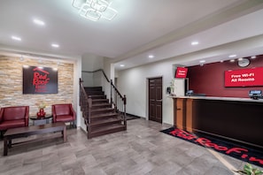 A hotel reception area with a staircase, seating, and a digital display indicating free Wi-Fi availability. - Red Roof Inn & Suites Carrollton, GA–West Georgia (Carrollton)