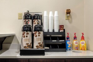 Un espace dédié au café, équipé de distributeurs de café, de tasses et de bouteilles de crème pour café.