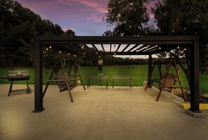 A covered outdoor seating area with swings and a barbecue grill. - Red Roof Inn & Suites Carrollton, GA–West Georgia (Carrollton)