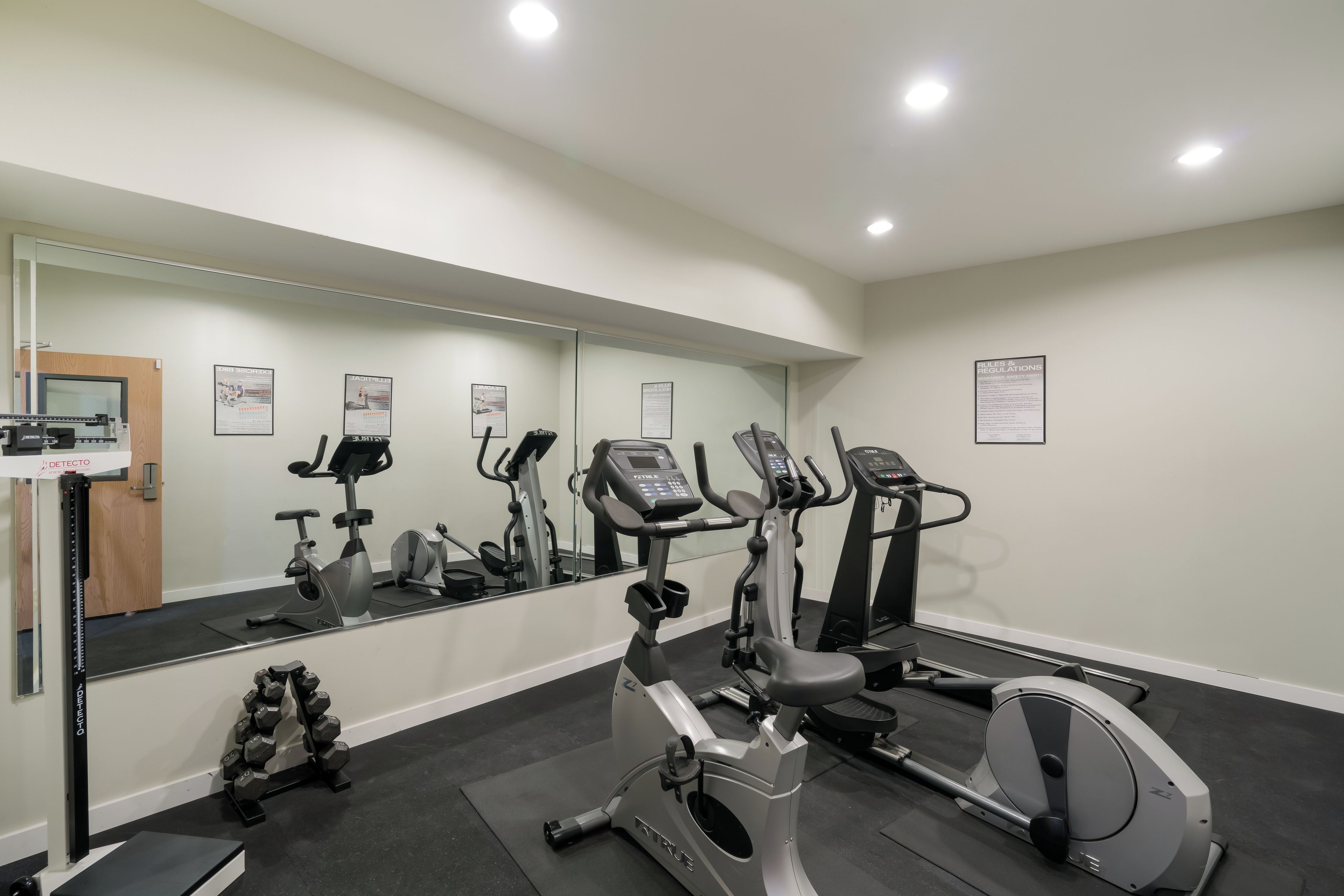 Un gimnasio con diversos equipos de ejercicio, un espejo y un cartel en la pared.