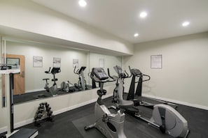 A gym with various exercise equipment, a mirror, and a wall-mounted sign. - Red Roof Inn & Suites Carrollton, GA–West Georgia (Carrollton)