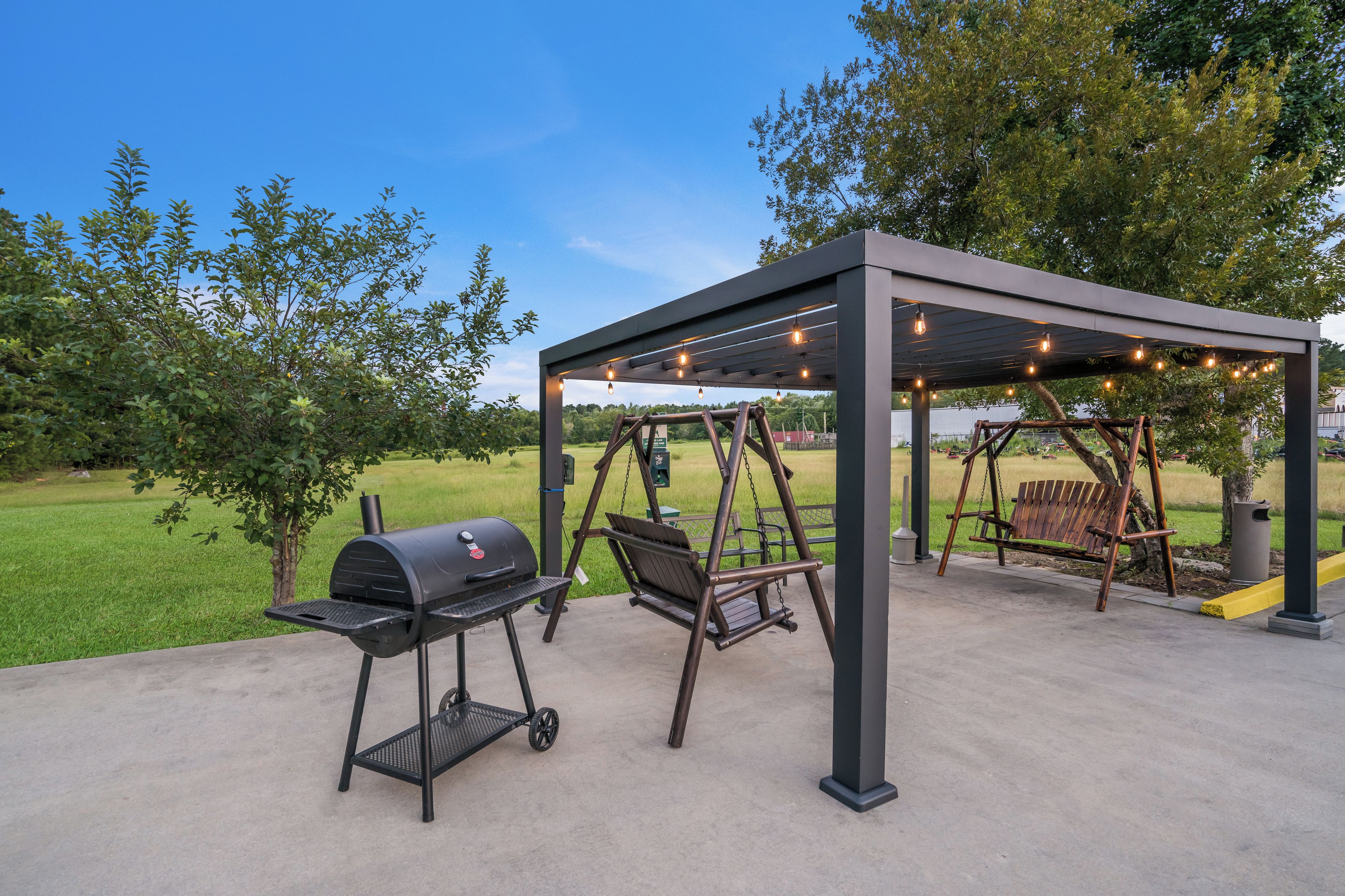 An outdoor patio with a grill, swing set, and string lights.