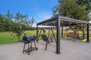 An outdoor patio with a grill, swing set, and string lights. - Red Roof Inn & Suites Carrollton, GA–West Georgia (Carrollton)