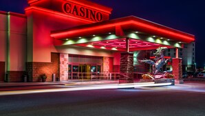 A casino building with a prominent red sign, a large entrance, and a decorative statue. - Deerfoot Inn & Casino (Calgary)