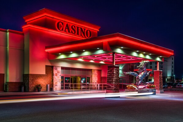 A casino building with a prominent red sign, a large entrance, and a decorative statue. - Deerfoot Inn & Casino (Calgary)