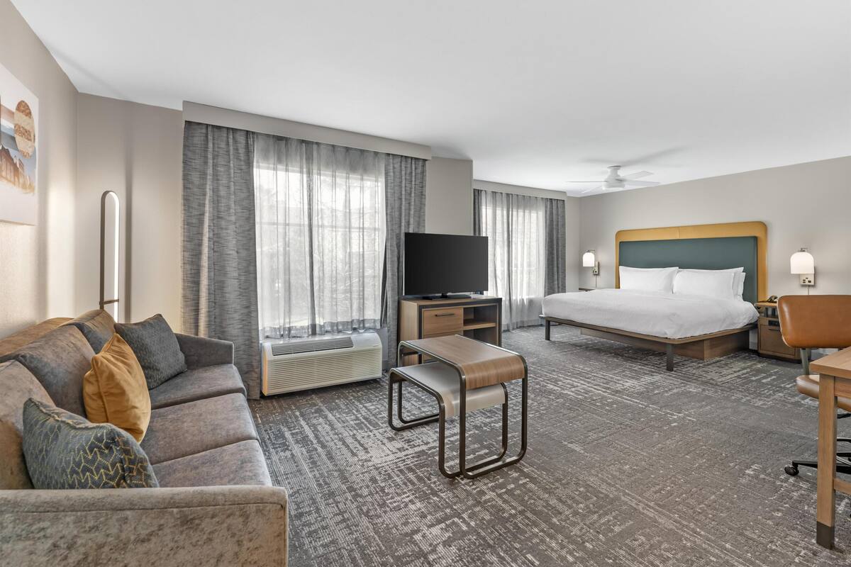 Ett hotellrum med en säng, en tv, en soffa, ett skrivbord och en stol.
