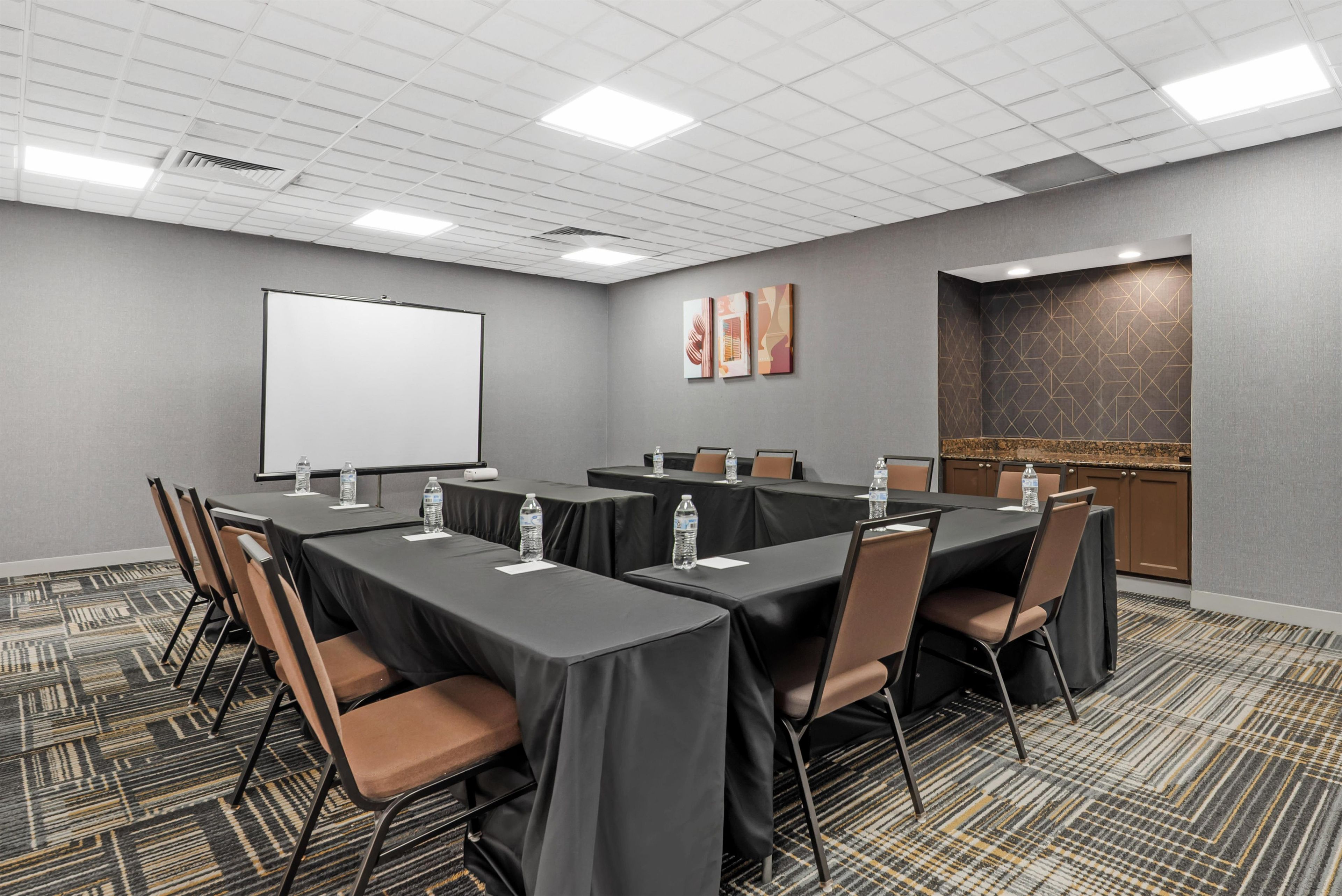 A conference room with a whiteboard, tables, chairs, and a water dispenser.