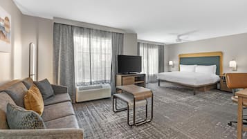 Een hotelkamer met een bed, een bank, een televisie en een bureau.