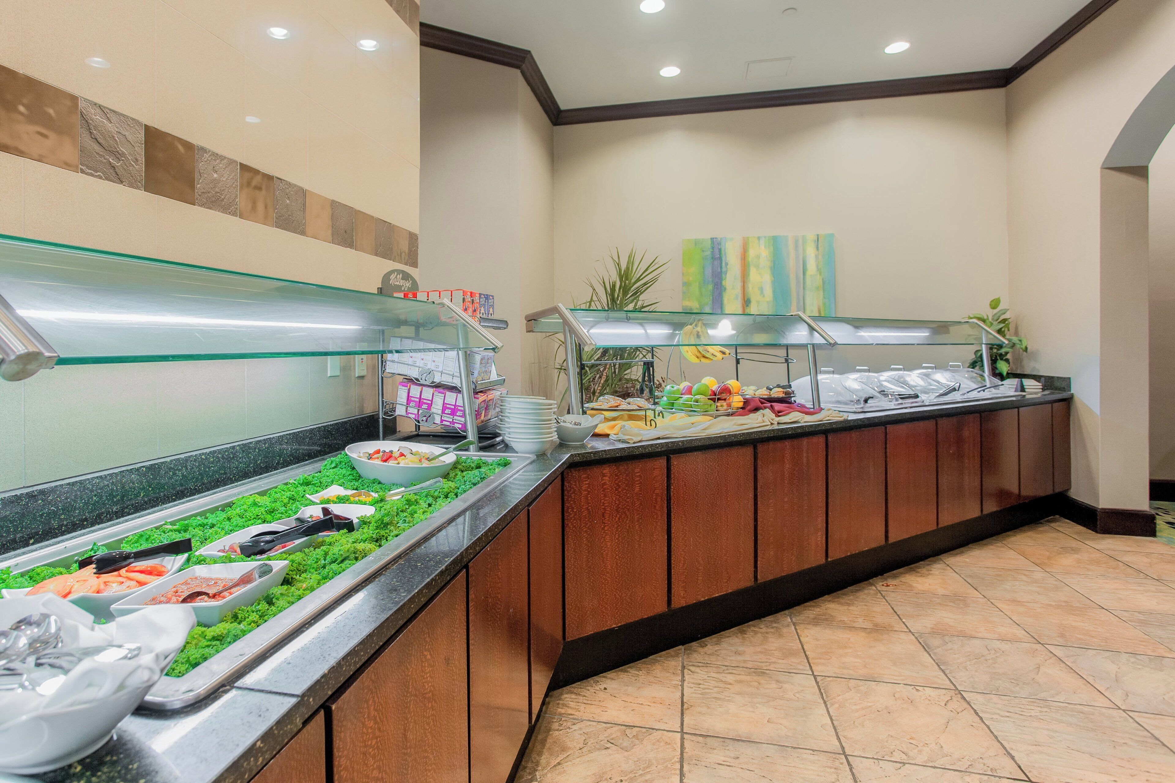 Zona de bufé con diversas opciones de comida, como ensaladas, frutas y bebidas.