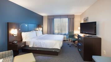 A hotel room with a large bed, bedside tables with lamps, a television, a desk, and a chair.