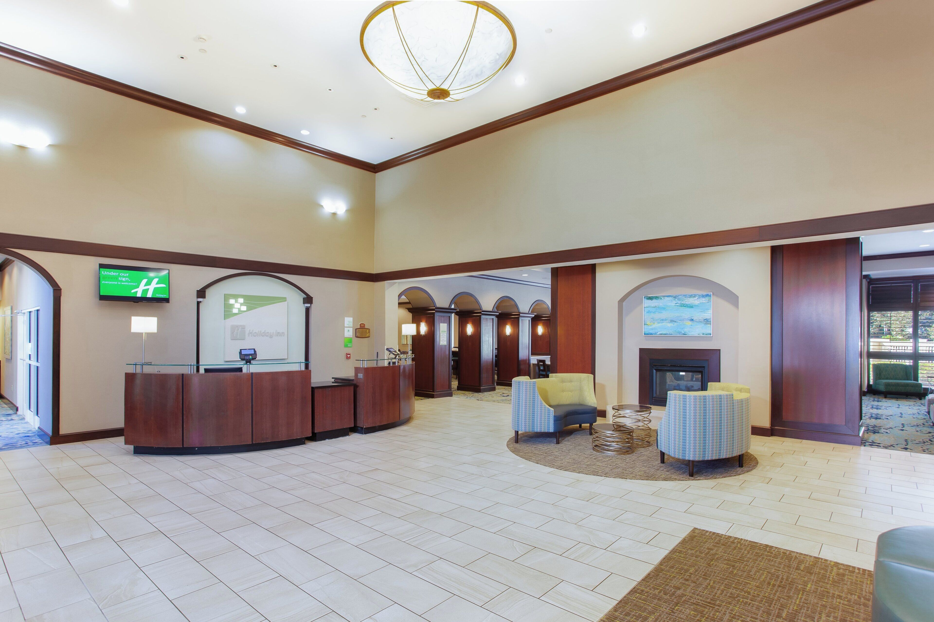 A hotel lobby with a reception desk, seating area, and a fireplace.