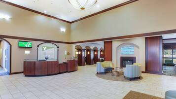 A hotel lobby with a reception desk, seating area, and a fireplace.