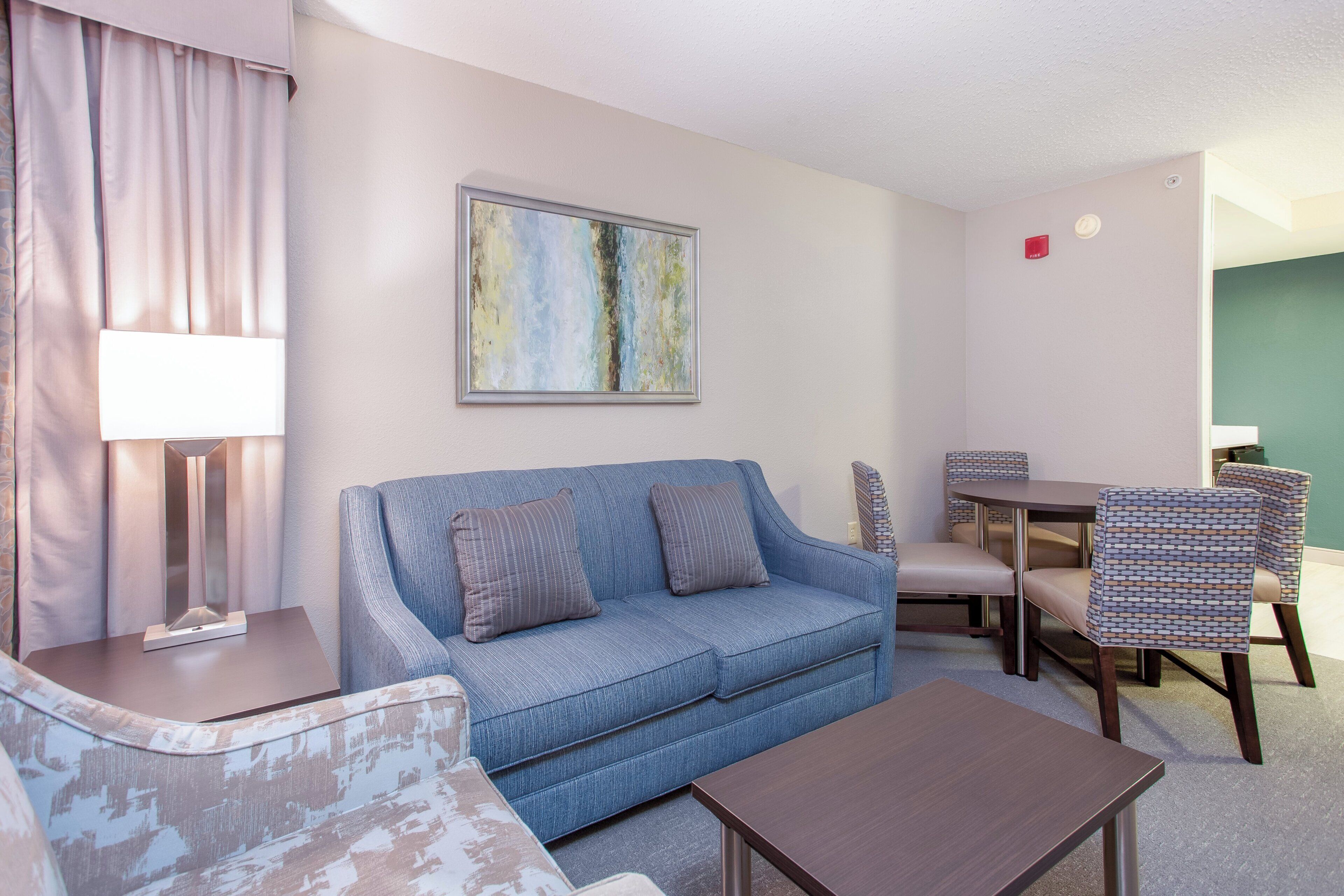 A living room with a blue sofa, a coffee table, a lamp, and a painting on the wall.