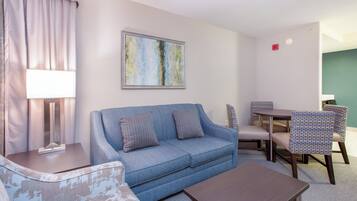 A living room with a blue sofa, a coffee table, a lamp, and a painting on the wall.