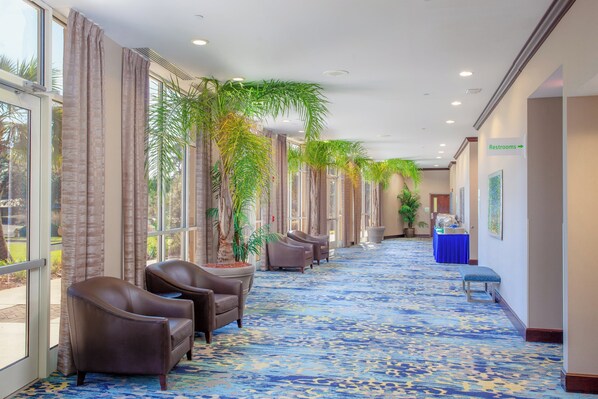 A hotel lobby with a long corridor, seating area, and a reception desk. - Holiday Inn Hotel & Suites Tallahassee Conference Ctr N by IHG (Tallahassee)