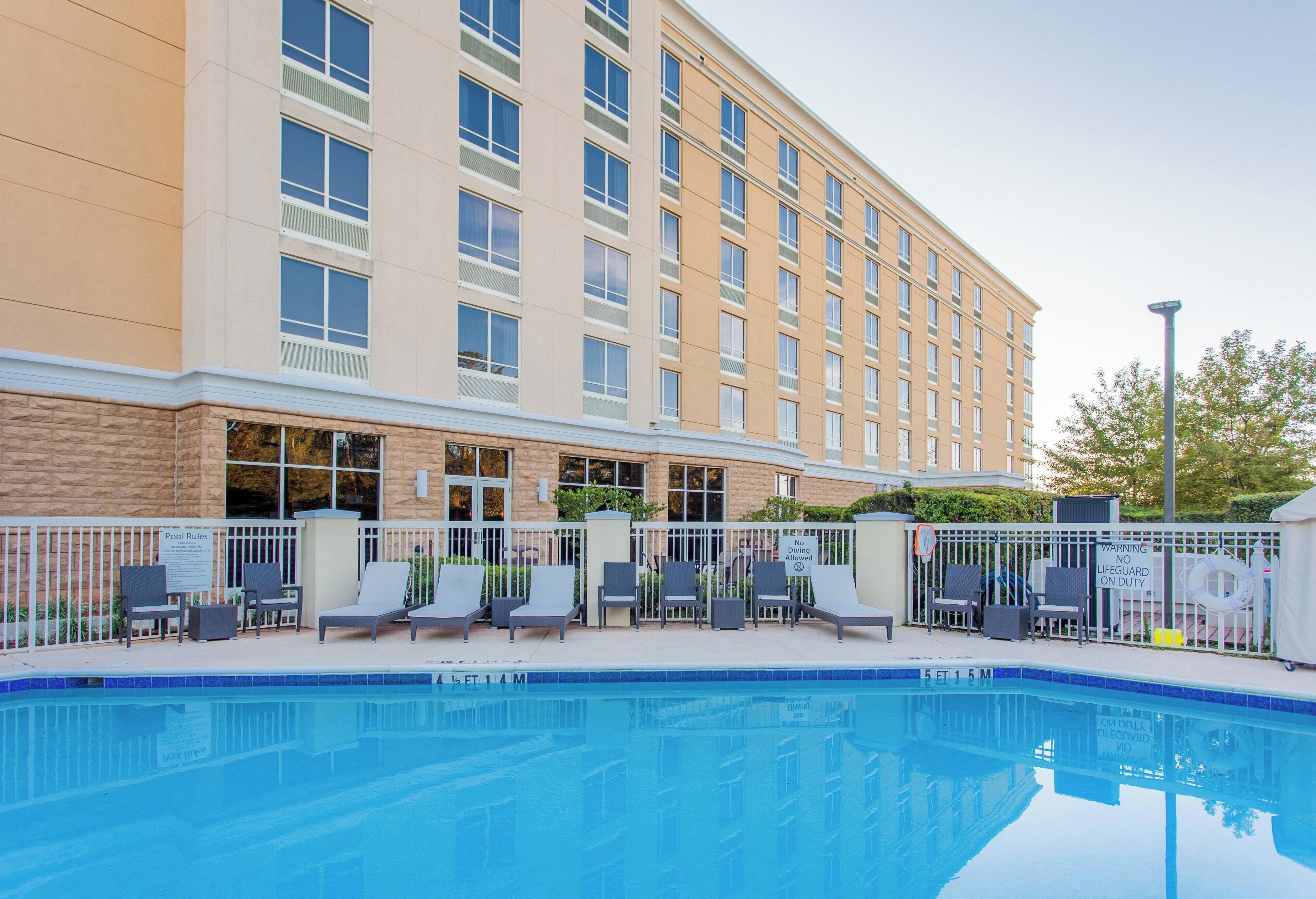 A hotel with a swimming pool, lounge chairs, and a sign indicating no diving allowed.