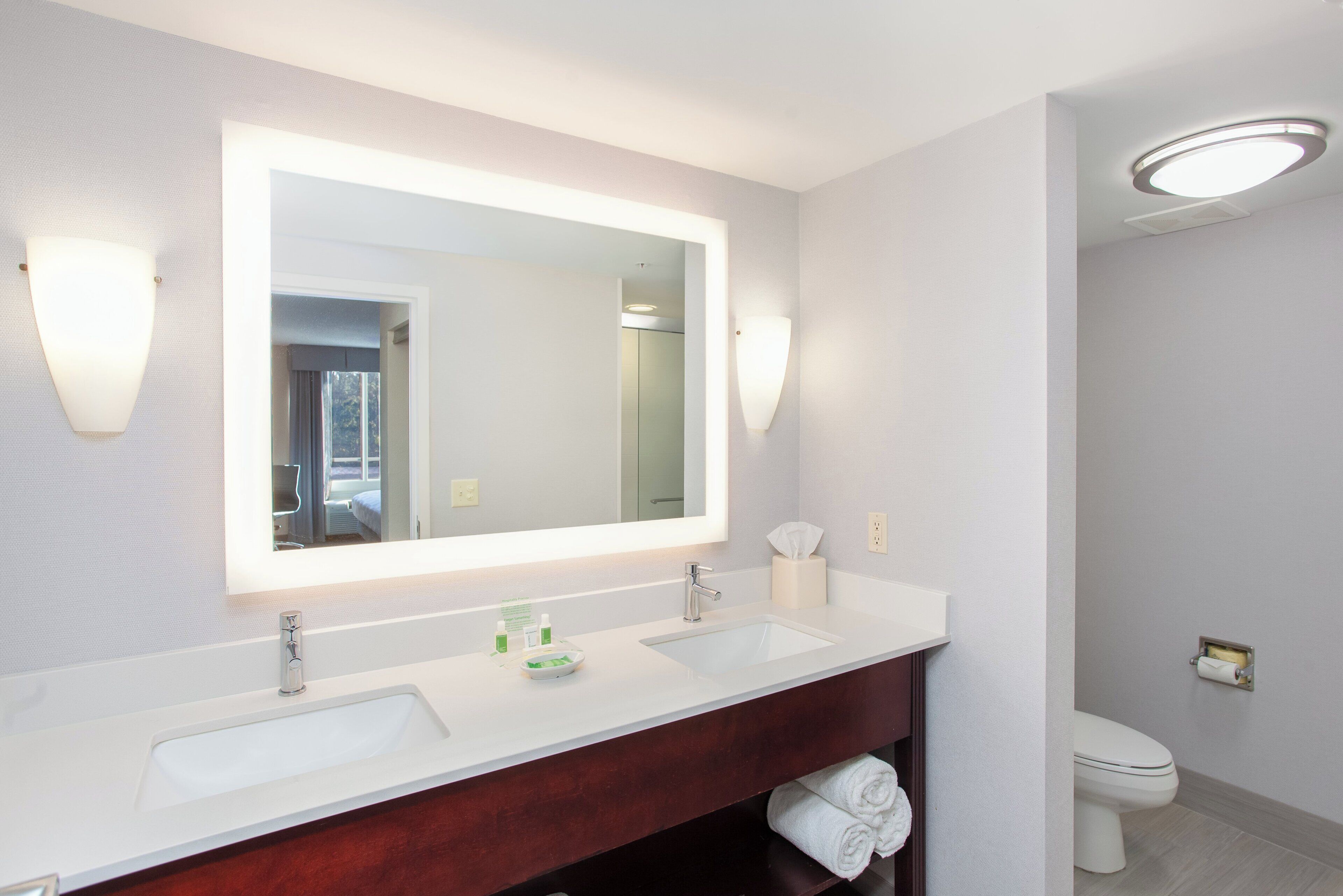 Un baño moderno con lavamanos doble, un espejo grande y un inodoro.