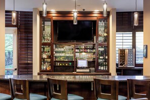 A bar area with a television, shelves of liquor bottles, and a cash register. - Holiday Inn Hotel & Suites Tallahassee Conference Ctr N by IHG (Tallahassee)
