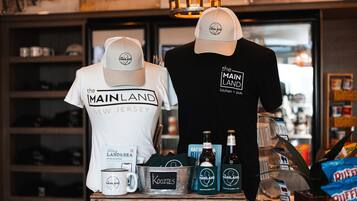 A display with merchandise including t-shirts and hats with "Mainland New Jersey" branding, a mug, and bottles labeled "Mainland".